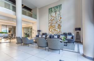 a lobby with chairs and tables and a painting on the wall at Menlyn Maine Trilogy Apartment 101 in Pretoria