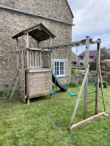 a wooden playground in a yard next to a building at Lower Farm in Sherborne