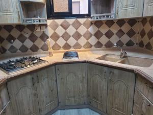 a kitchen with wooden cabinets and a stove and a sink at شقة لين طيبة للعوائل Leen Taibah Ap. for family's in Al Madinah +14 photos