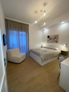 um quarto branco com uma cama e uma cadeira em La casa di Toto em Nápoles