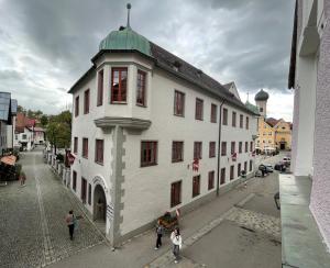 un grand bâtiment blanc avec un toit vert dans une rue dans l'établissement Italienische Gastfreundlichkeit im Herzen von Immenstadt, à Immenstadt