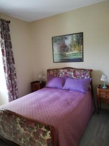 sypialnia z łóżkiem z fioletową pościelą i zdjęciem na ścianie w obiekcie LA MAISON D'ALIDA w mieście Nueil-sous-Faye