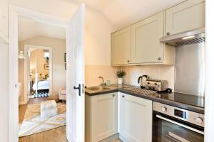 a kitchen with white cabinets and a sink at The Pigsty in Buxton