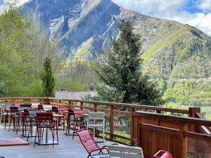 Chalet Le Panoramique في Mizoën: فناء به طاولات وكراسي على شرفة بها جبال