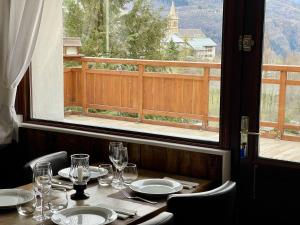 a table with plates and glasses and a window at Chalet Le Panoramique in Mizoën