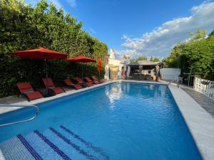 a large swimming pool with red chairs and umbrellas at Villa GAN EDEN in La Drova