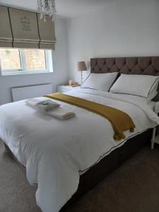uma cama grande com lençóis brancos e um cobertor castanho em Claro Mews Gem em Knaresborough