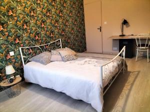 Bett in einem Zimmer mit einer Wand mit Blumen in der Unterkunft Chez Nadine in Valframbert