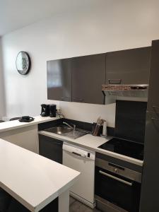 a kitchen with white counters and black cabinets at Le Havre, 1 chambre , appartement Sympa en centre ville in Le Havre
