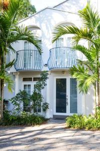 a white house with palm trees in front of it at Coconut Grove Hidden Sanctuary Townhouse in Miami