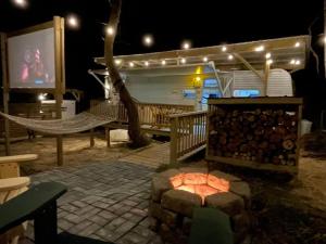 een vuurplaats met een hangmat en een scherm bij Ramblin Rose Camper - Theater - Hot-Tub - Fire Pit 