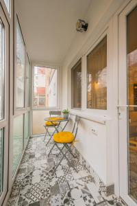 einen Balkon mit 2 Stühlen, einem Tisch und Fenstern in der Unterkunft Kitty Sunflower Apartment in Alba Iulia