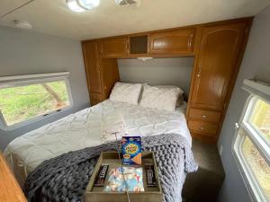 een kleine slaapkamer met een bed in een camper bij Ramblin Rose Camper - Theater - Hot-Tub - Fire Pit 