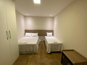 a small room with two beds and a table at Pousada Mineira SJB in São João da Barra