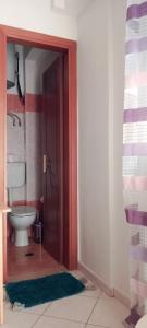 a bathroom with a toilet and a door in a room at Studio near University of Thessaly in Larisa