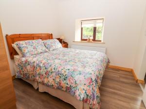 um quarto com uma cama com uma colcha floral e uma janela em Sweeney's Cottage em Beaufort
