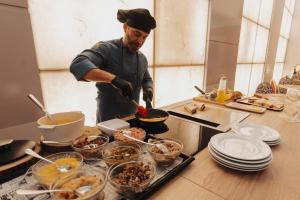 a man in a kitchen preparing food on a counter at Gran Hotel Don Manuel in Cáceres