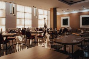 a dining room with tables and chairs and windows at Gran Hotel Don Manuel in Cáceres