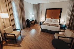 a hotel room with a bed and a desk and chairs at Gran Hotel Don Manuel in Cáceres