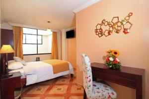 a bedroom with a bed and a desk and a chair at La Rosario Hotel in Quito +44 photos