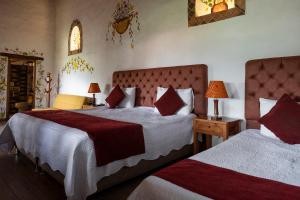 a bedroom with two beds with red and white sheets at Hotel Spa Casa de Adobe Villa de Leyva in Villa de Leyva
