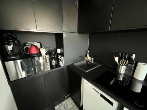 a black kitchen with a sink and a counter at Un été sans fin à Deauville in Deauville