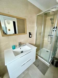 La salle de bains blanche est pourvue d'un lavabo et d'une douche. dans l'établissement Un été sans fin à Deauville, à Deauville