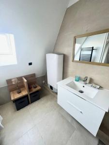 La salle de bains est pourvue d'un lavabo blanc et d'un miroir. dans l'établissement Un été sans fin à Deauville, à Deauville