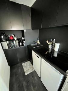a small kitchen with black walls and white cabinets at Un été sans fin à Deauville in Deauville