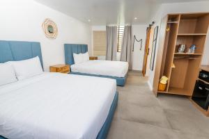 um quarto de hotel com duas camas e uma televisão em Parguera Plaza Hotel - Adults Only em La Parguera