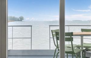 een veranda met een tafel en stoelen en uitzicht op de oceaan bij Nice Ship In Biddinghuizen With Kitchen in Biddinghuizen