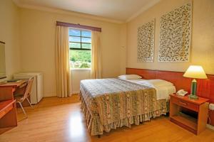ein Hotelzimmer mit einem Bett und einem Fenster in der Unterkunft Hotel Monte Real in Águas de Lindóia