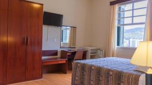 a bedroom with a bed and a desk and a window at Hotel Monte Real in Águas de Lindoia
