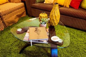 a glass coffee table with a book and a vase at Retro-inspired Content House In Patterson Park in Baltimore