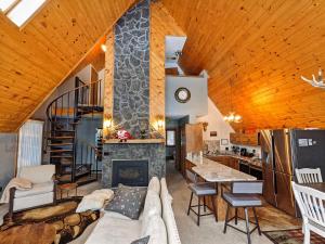a living room with a stone fireplace and a staircase at Wildlife Chalet - Sauna Lakeview Firepit Wifi in Tofte
