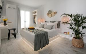 a white bedroom with a bed and a plant at Naxos Hotel Poseidon in Naxos Chora