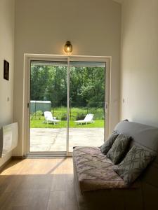 a bedroom with a bed and a sliding glass door at Makivka - A 5 min de Cognac - Maison entière avec 2 chambres in Boutiers-Saint-Trojan