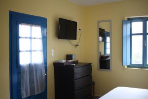 sypialnia z niebieskimi drzwiami, komodą i telewizorem w obiekcie Μικρό Ανάδιο w mieście Kapsálion