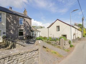a cottage and a stone wall next to a street at Beech Cottage in Ulverston