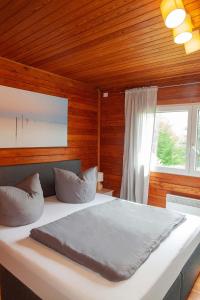 a bedroom with a bed with wooden walls and a window at Ferienhaus Auszeit in Lindenfels