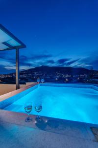a swimming pool with two wine glasses on top of a building at Villa Mare Syros in Finikas