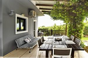 a patio with a wooden table and chairs and a couch at marathon family villa in Schinias