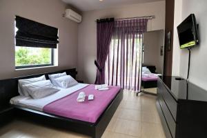 a bedroom with a bed with purple sheets and a tv at marathon family villa in Schinias