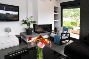 a living room with a fireplace and a vase of flowers at marathon family villa in Schinias