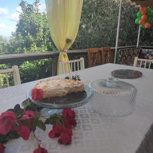 einen Kuchen auf einem Teller auf einem Tisch mit Rosen in der Unterkunft Casa Container in Santo Antônio