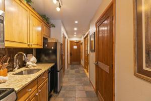a kitchen with wooden cabinets and a sink and a refrigerator at Riverbend Centennial Run Condo: Ski In/Out in Breckenridge