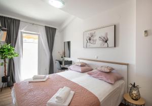 ein Schlafzimmer mit einem großen Bett mit rosa Kissen in der Unterkunft Apartmani Rita in Baška Voda