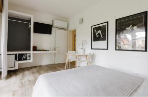 una camera bianca con letto e TV a schermo piatto di Relax & Emozioni Rooms a Valeggio sul Mincio