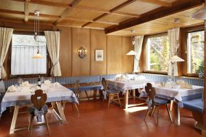 une salle à manger avec des tables blanches, des chaises et des fenêtres dans l'établissement Parkhotel Tirolerhof, à Lagundo