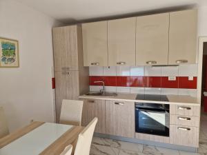uma cozinha com armários brancos e uma mesa com cadeiras em Apartment Elena em Dramalj
